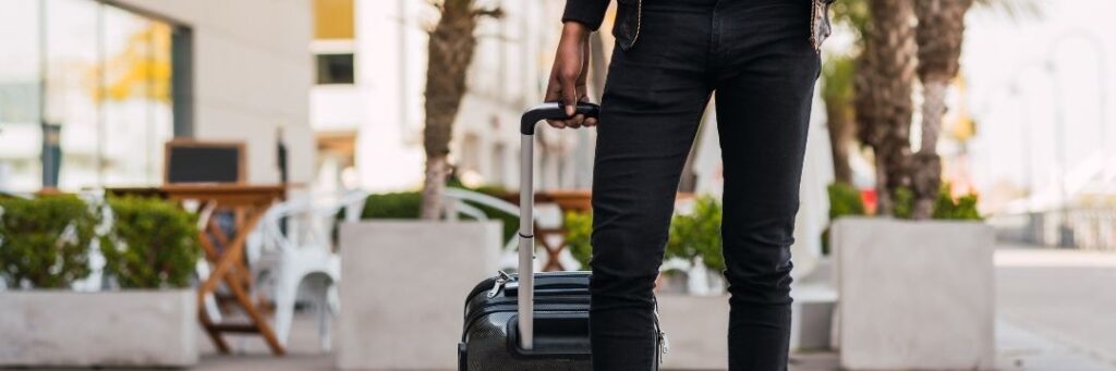 Man pulling suitcase through parking lot