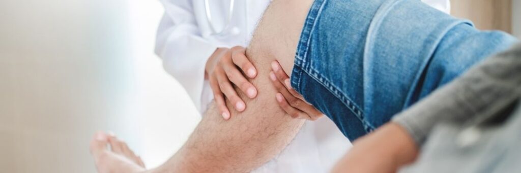 Man at orthopedic clinic consultation for limb lengthening surgery, provider holding and bending leg